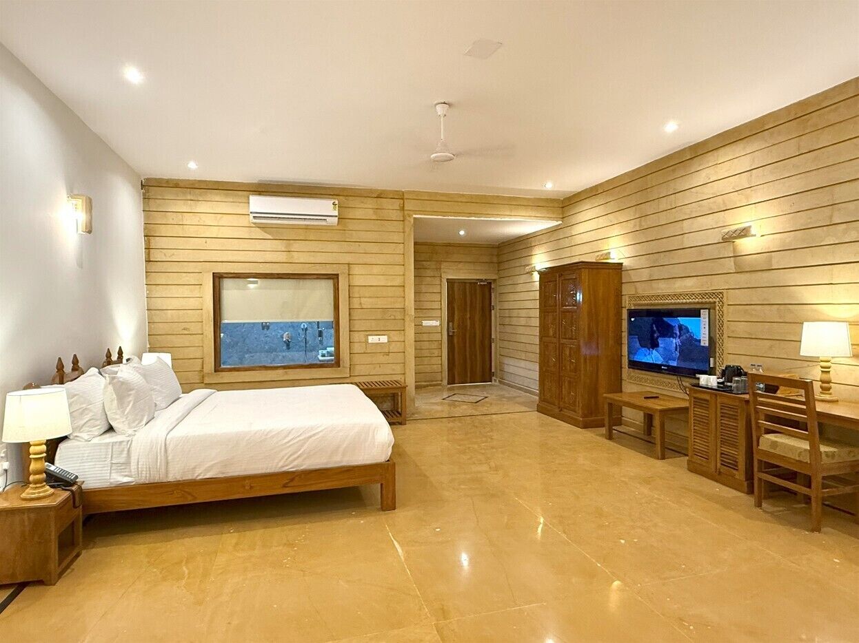 Habitación de hotel moderna con panel de pared de madera, una cama grande, un televisor y un escritorio con una silla.