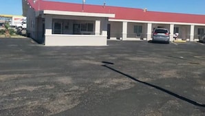 A building with a red roof and multiple parking spaces. - Budget Inn Fort Stockton (Fort Stockton)