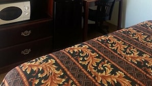 A hotel room with a bed, a desk, a chair, a television, and a mirror. - Budget Inn Fort Stockton (Fort Stockton)