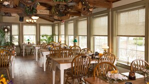 A dining area with wooden tables and chairs, large windows, and ceiling decorations including a 'RELAX' sign. - 1825 Inn Bed and Breakfast (Palmyra)