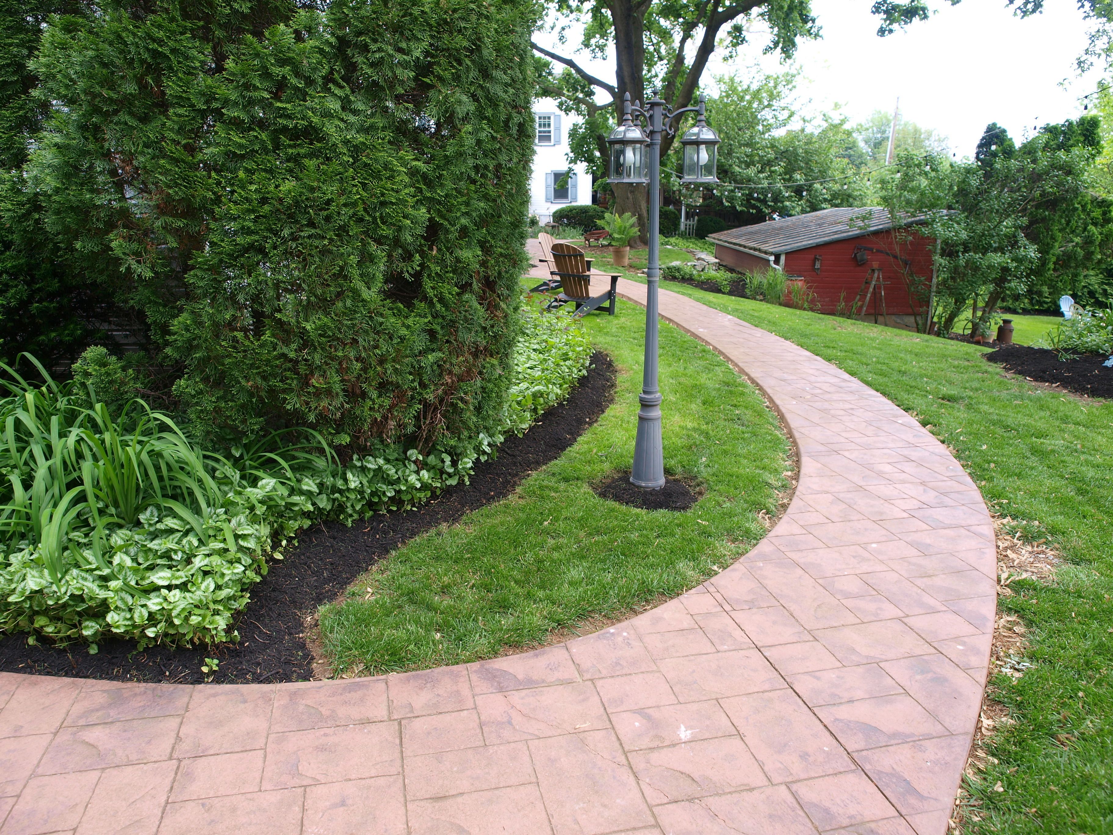 A curved brick pathway in a landscaped garden area.