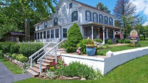 A large, two-story white house with a porch and a flag. - 1825 Inn Bed and Breakfast (Palmyra)