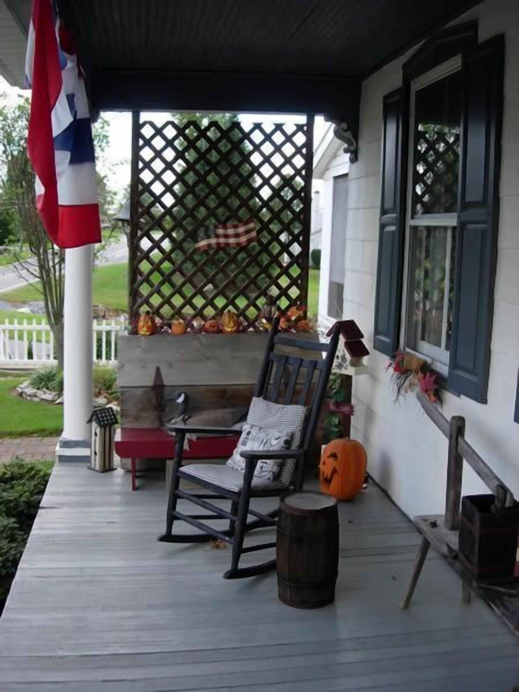 A porch with a rocking chair, a small table, and a pumpkin decoration.