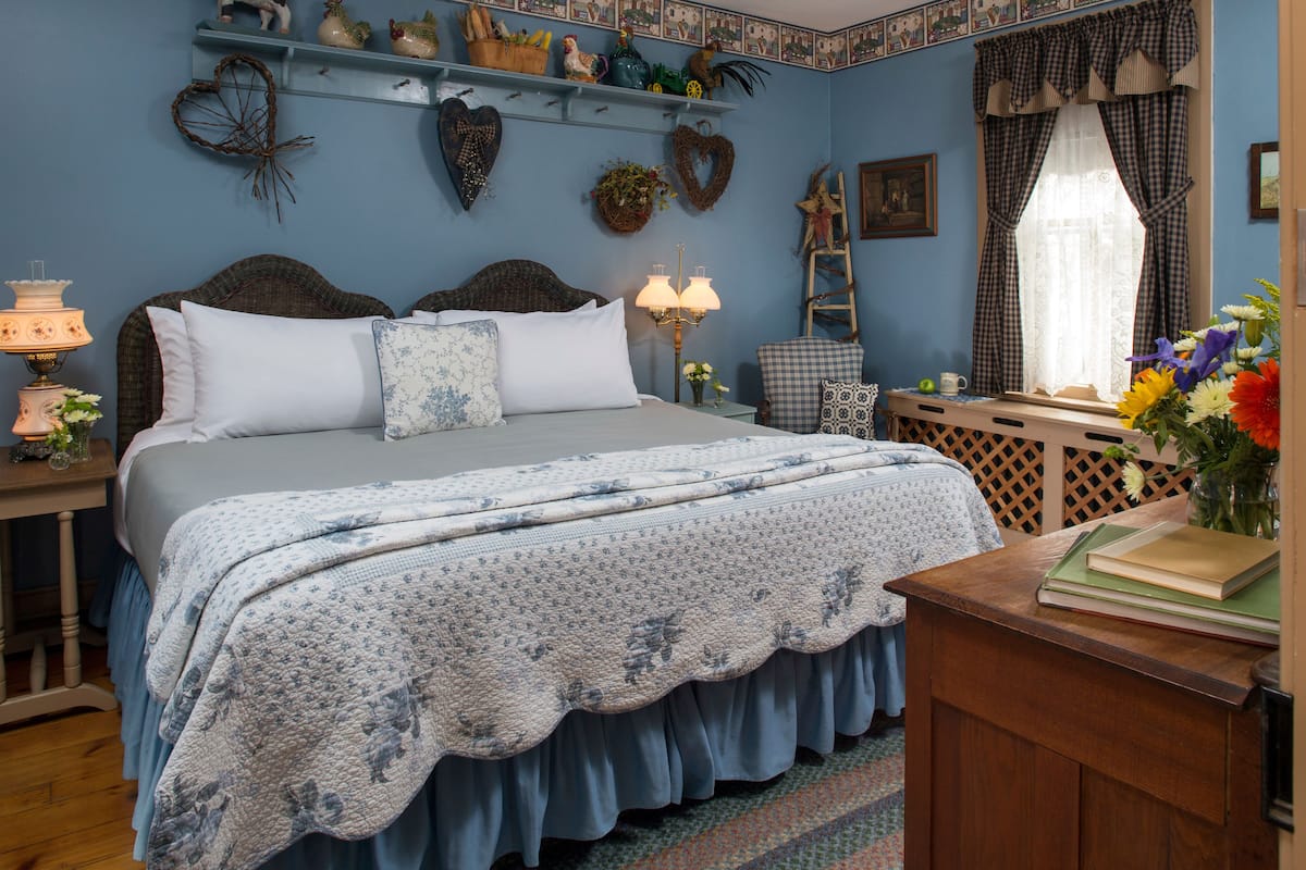 A bedroom with a bed, bedside table, lamp, and decorative items on the wall.