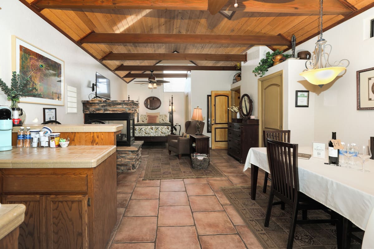 A spacious kitchen with a large island, wooden ceiling beams, and a dining area with a table set for a meal.