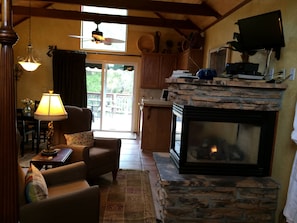A cozy living room with a fireplace, a dining area with a table and chairs, and a kitchen with a stone fireplace. - Creekside Inn of Paso Robles (Paso Robles)