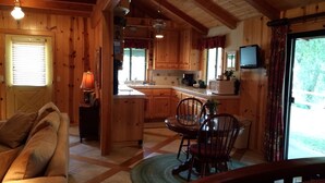 A cozy cabin interior with a dining area, kitchen, and a living room with a sofa. - Creekside Inn of Paso Robles (Paso Robles)