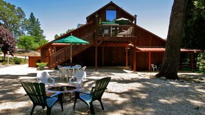 A wooden cabin with a deck, outdoor seating, and a gravel patio. - Creekside Inn of Paso Robles (Paso Robles)