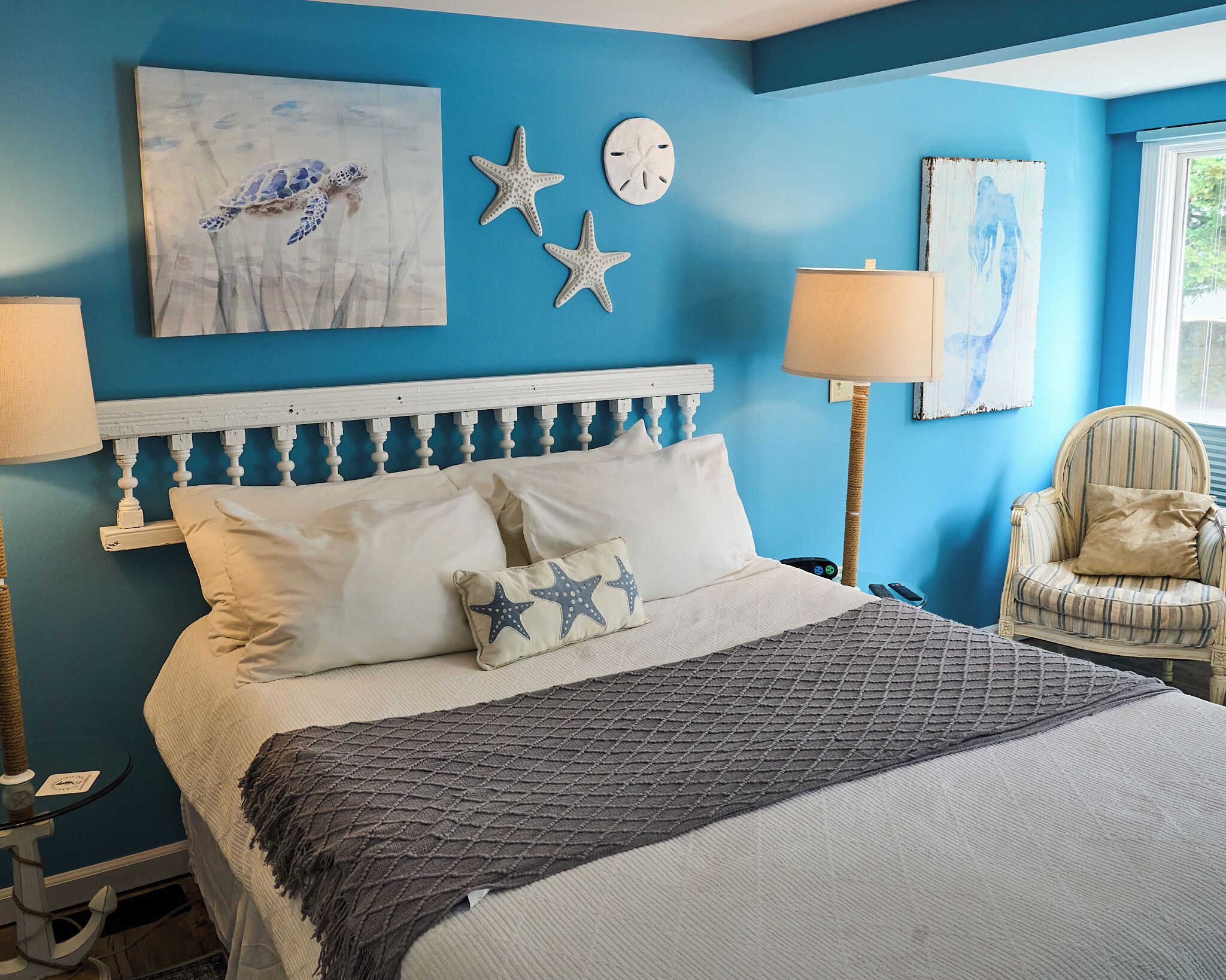 A bedroom with a bed, starfish decorations, a clock, and a chair.
