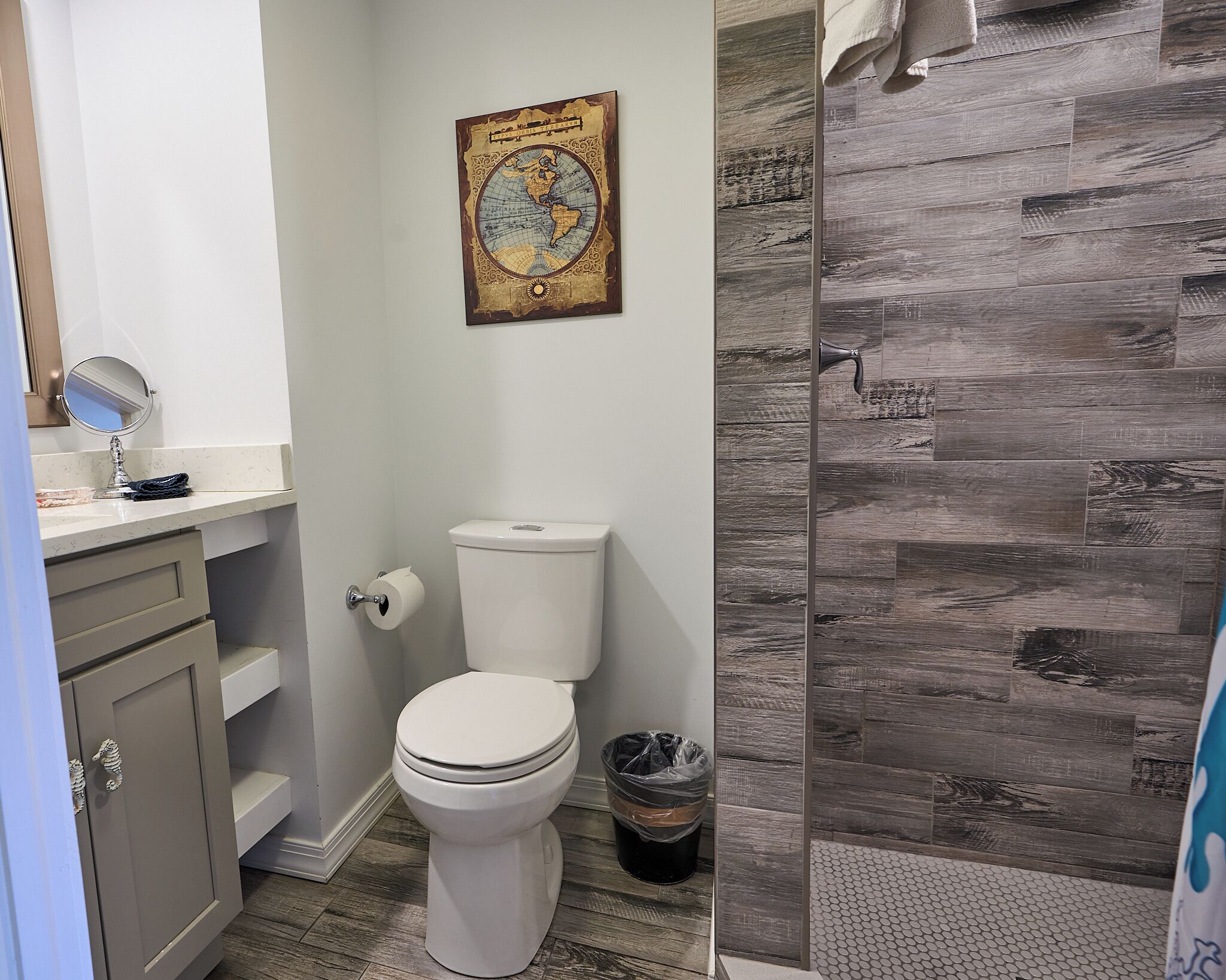 Une salle de bain comprenant des toilettes, un lavabo avec un miroir, un rouleau de papier toilette et une poubelle.