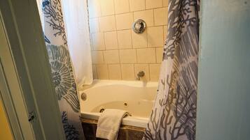 A bathroom with a bathtub, tiled walls, and a shower curtain.