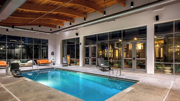 An indoor swimming pool with clear blue water, surrounded by lounge chairs and a modern interior design.