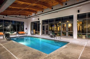 Une piscine intérieure à l’eau d’un bleu cristallin, entourée de chaises longues et dotée d’un aménagement intérieur moderne.