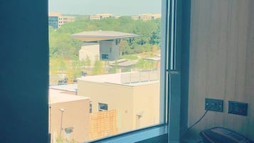 Una habitación con un amplio ventanal que da a un campus con edificios y árboles.