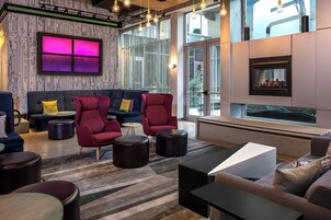 Un salon moderne comprenant un canapé, des fauteuils et des poufs, une cheminée et de grandes fenêtres.