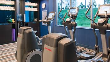 A gym with stationary bikes, a water dispenser, and a trash bin.