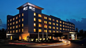 A modern hotel building with a prominent 'Aloft Hotels' sign, multiple floors, and a well-lit entrance.