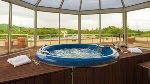 A hot tub with a glass enclosure, wooden deck, and a view of the landscape. - Grand Hotel Primus - Sava Hotels & Resorts (Ptuj)