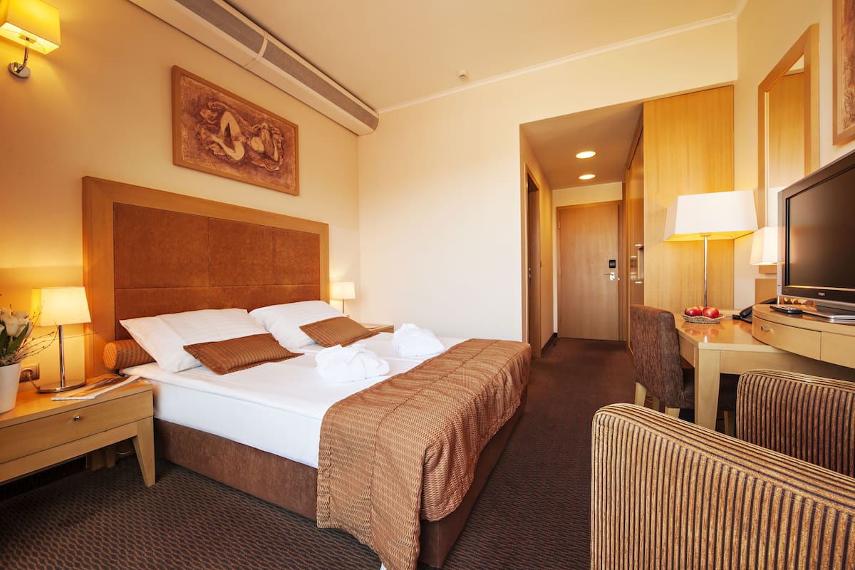 Ein Hotelzimmer mit einem großen Bett, einem Schreibtisch mit Fernseher und einer Essecke.