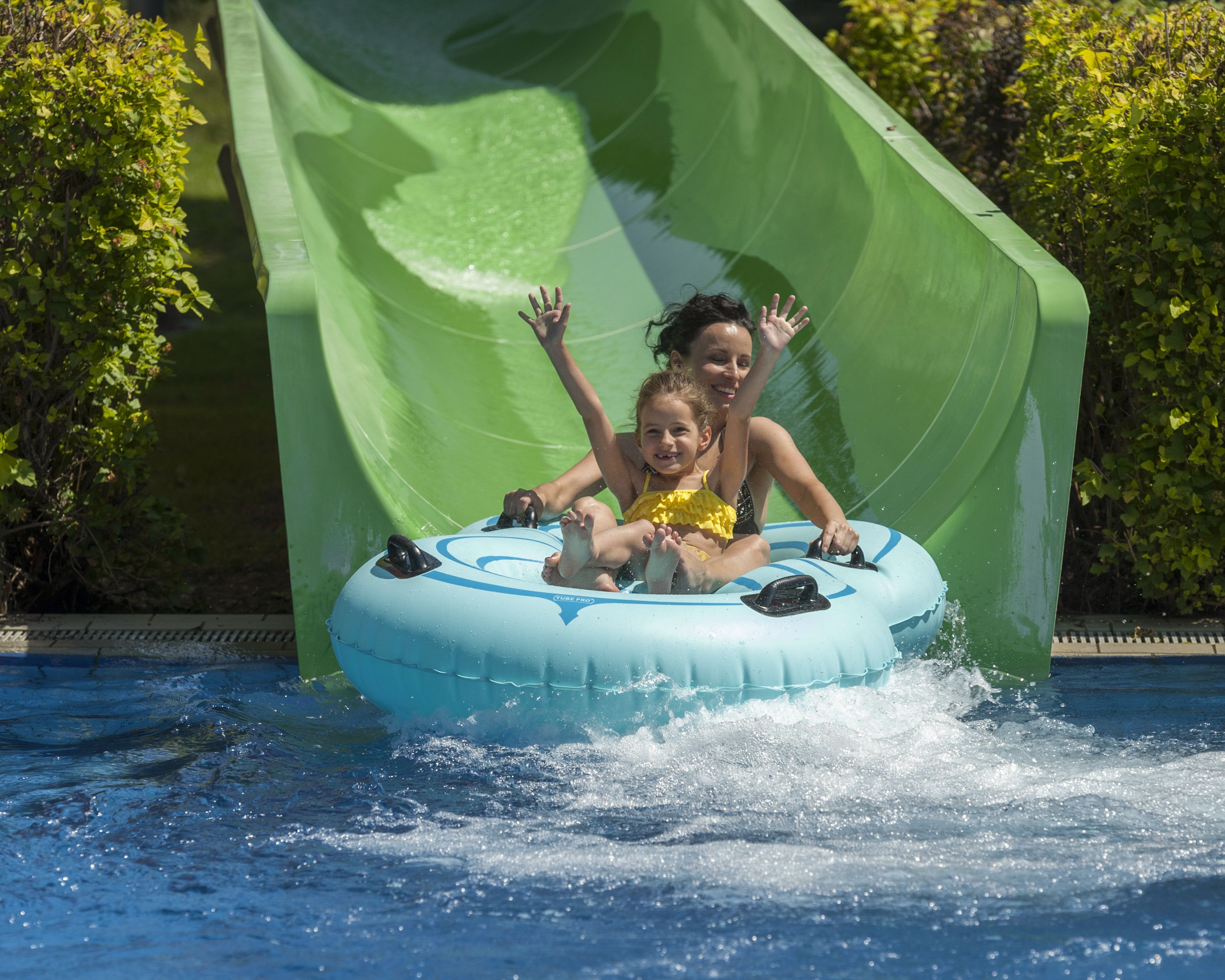 Dos personas en un tobogán acuático dentro de una piscina.