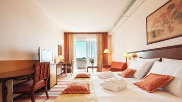 A hotel room with a bed, a desk, a chair, and a window with curtains.