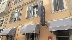 A hotel facade with multiple windows, awnings, and a sign indicating the hotel name. - Hotel Anna Livia (Cannes)