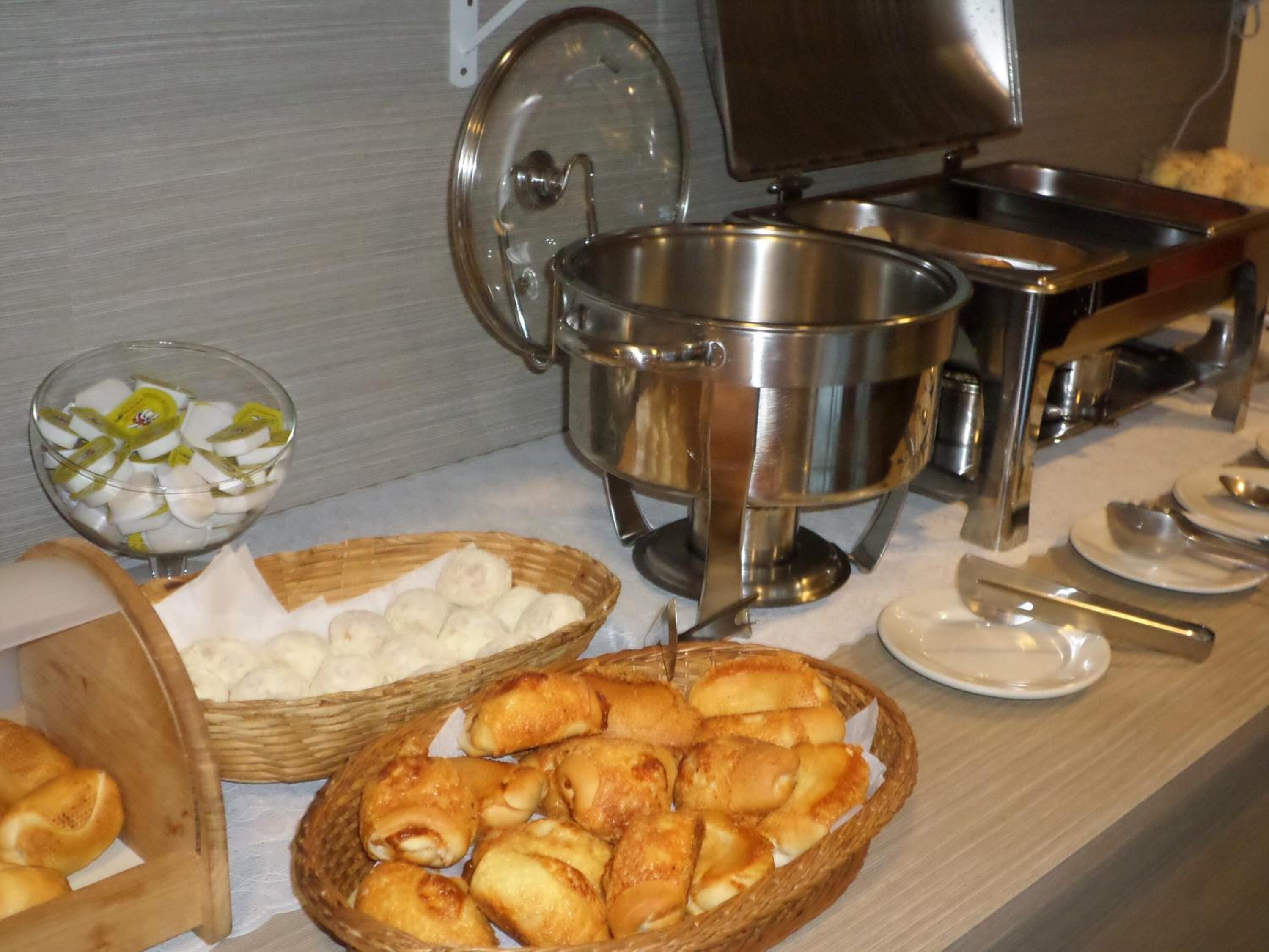A buffet setup with various food items, including baskets of pastries and a bowl of sliced fruit.