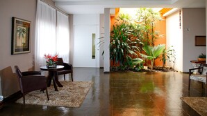 A spacious living room with a large plant area, a dining set, and a framed picture on the wall.
