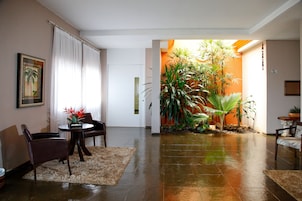Un salón amplio con una zona de plantas grande, un comedor y un cuadro en la pared.