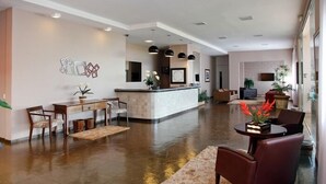 A spacious lobby with a reception desk, seating area, and a large mirror.
