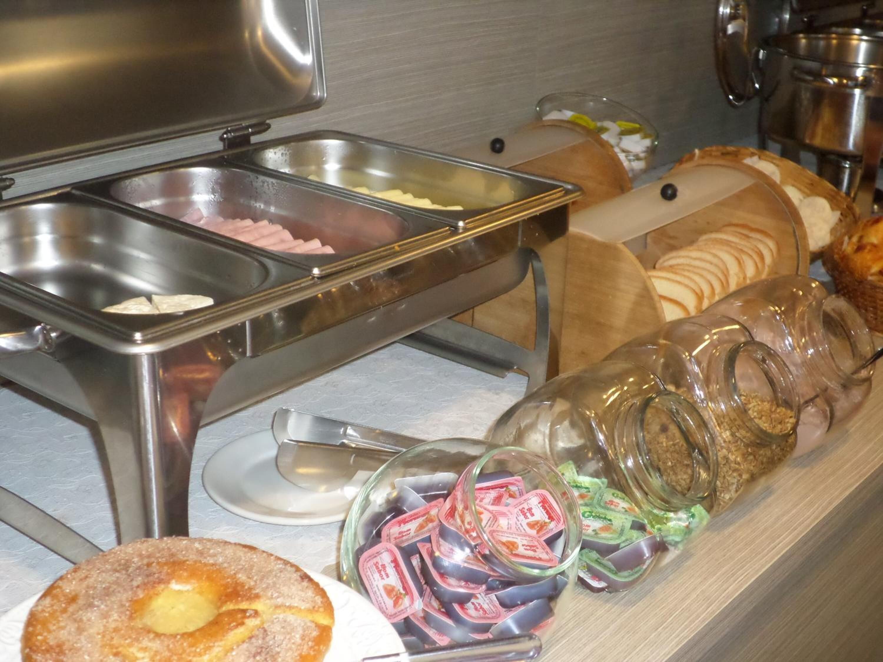 A buffet with various food items including bread, pastries, and condiments.