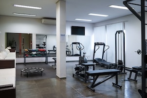 Un gimnasio con equipo de ejercicio, un espejo y una televisión en la pared.