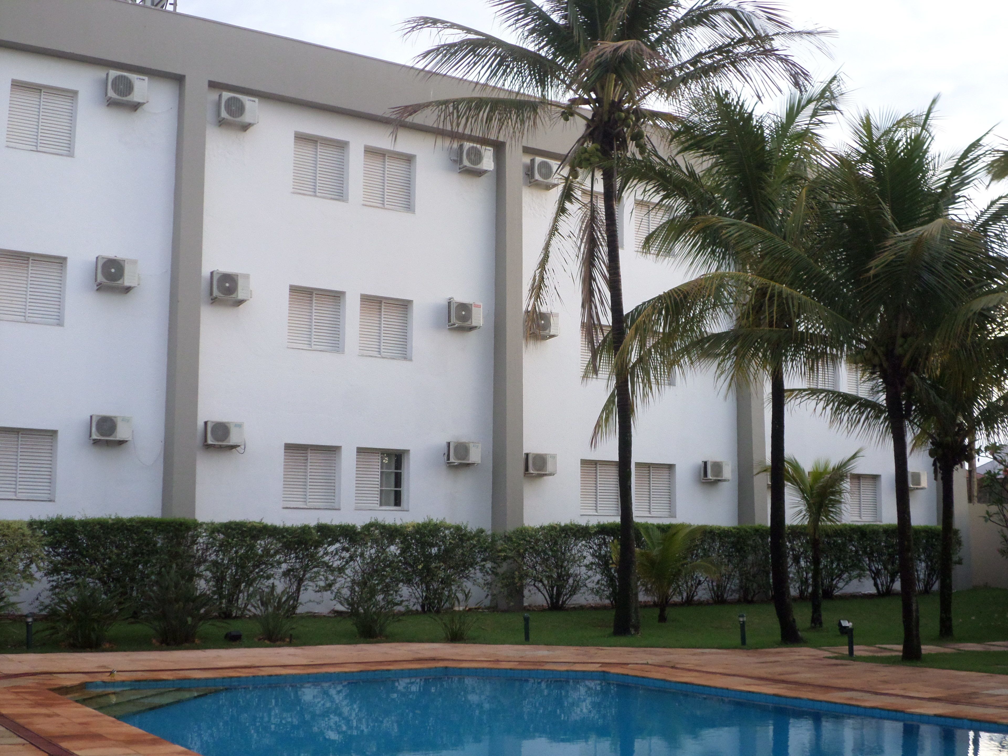 A building with multiple air conditioning units, a swimming pool, and palm trees.
