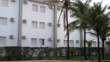 A building with multiple air conditioning units, a swimming pool, and palm trees.