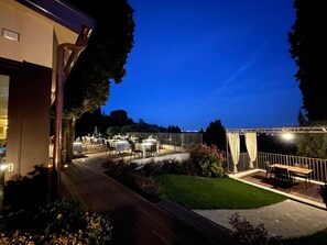 An outdoor dining area with tables and chairs, surrounded by a wooden deck and a grassy lawn. - Villa Giorgia Albergo In Collin (Pistoia)