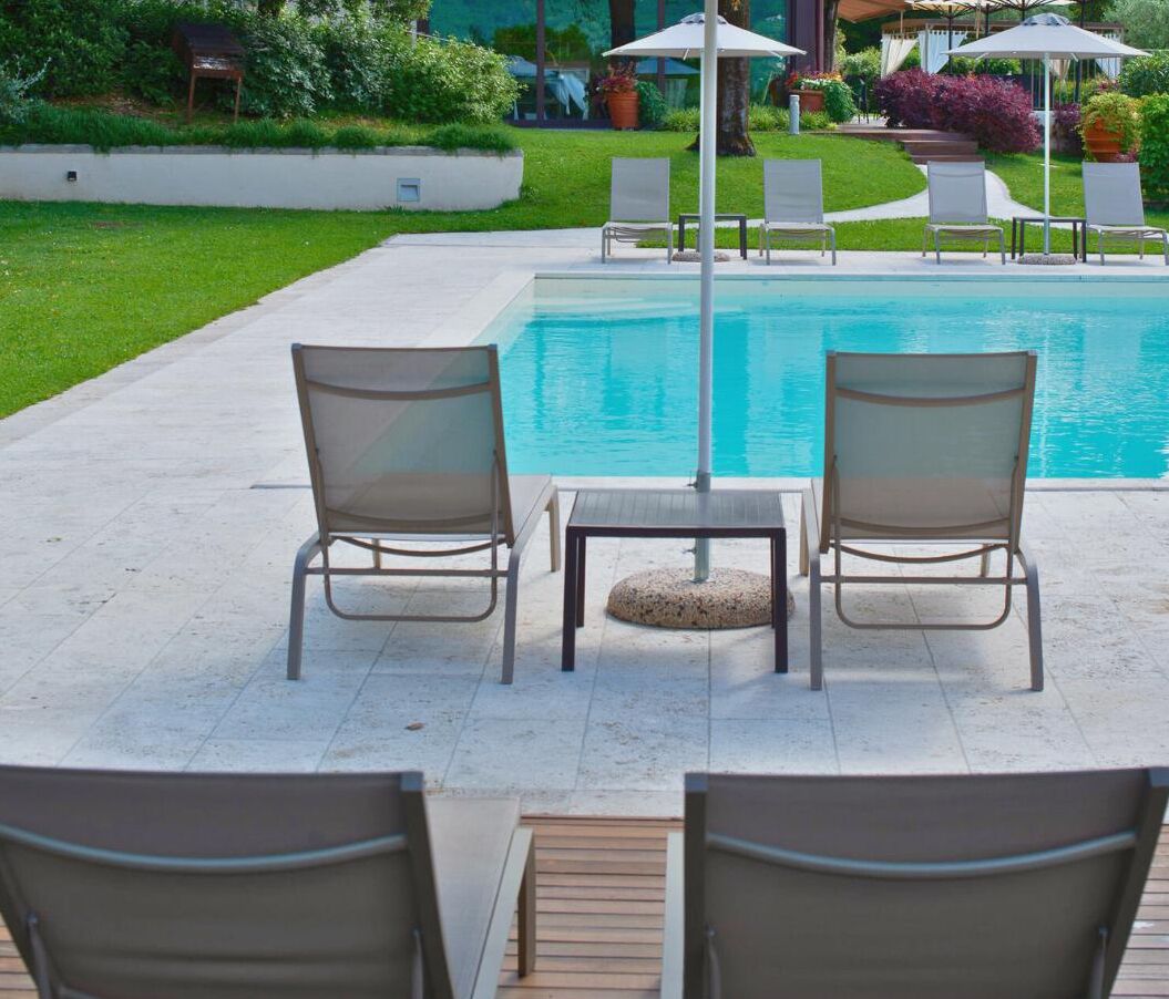 Un área junto a la piscina con dos sillones, una mesa y sombrillas.