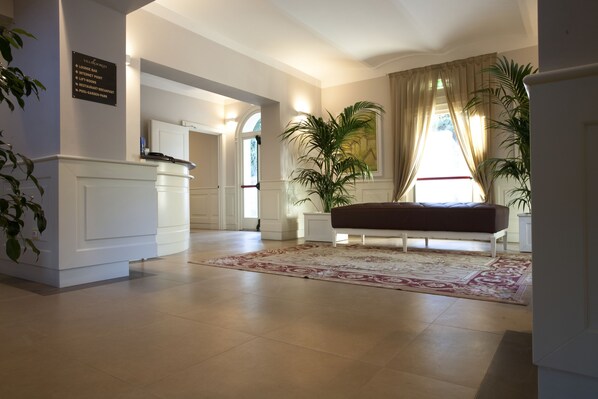 A spacious lobby with a reception desk, a bench, and a large potted plant. - Villa Giorgia Albergo In Collin (Pistoia)