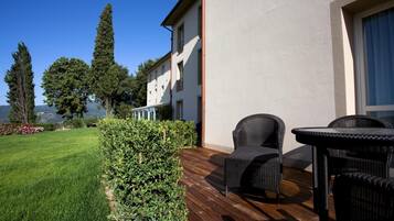 A patio with wicker furniture, a wooden deck, and a view of a mountain.