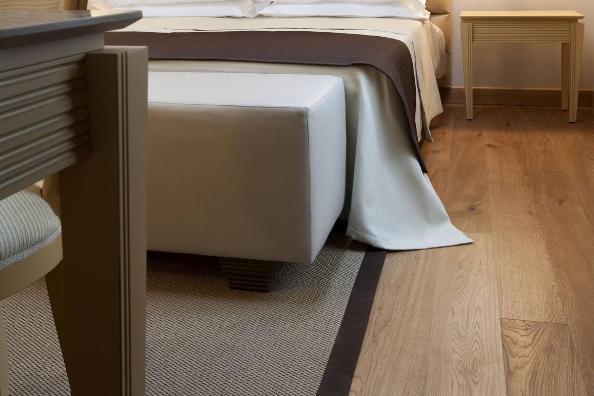 A hotel room with a bed, bedside table, lamp, and a chair.