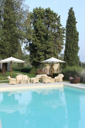A swimming pool with lounge chairs and umbrellas, surrounded by trees. - Villa Giorgia Albergo In Collin (Pistoia)
