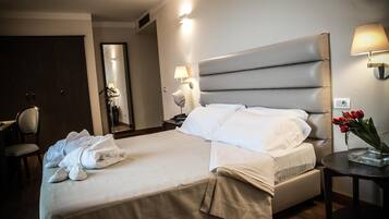 Habitació d'hotel amb un llit gran, una taula de nit, una cadira i un escriptori.