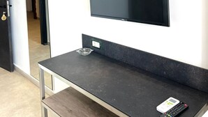 Habitació moderna amb televisió de pantalla plana penjada a la paret, un taulell fosc i un comandament petit al taulell.