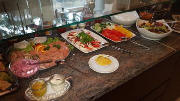 Ein reichhaltiges Buffet mit verschiedenen Speisen, darunter Fleisch, Salate und Dips.
