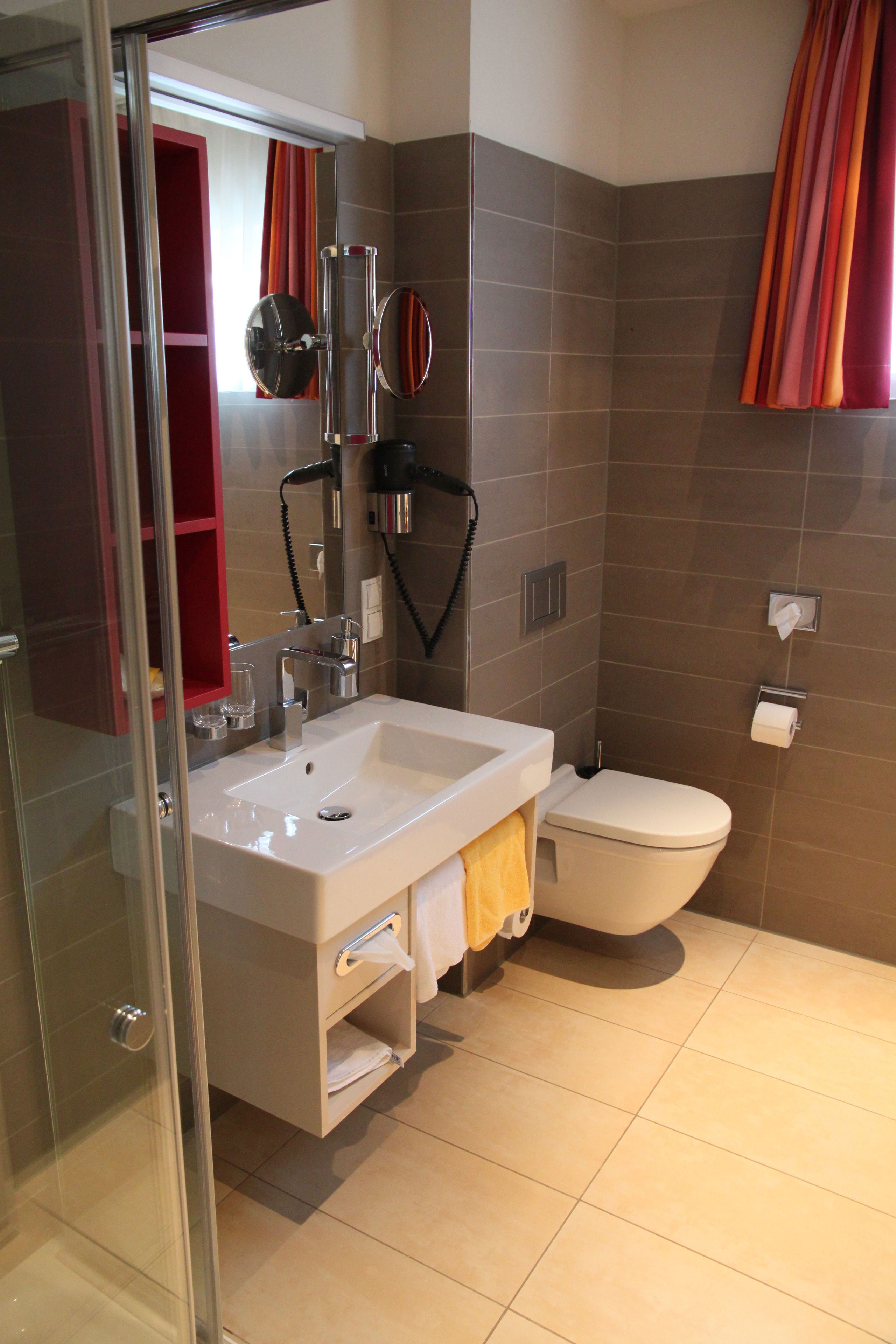 A modern bathroom with a glass shower enclosure, a white sink, and a toilet.