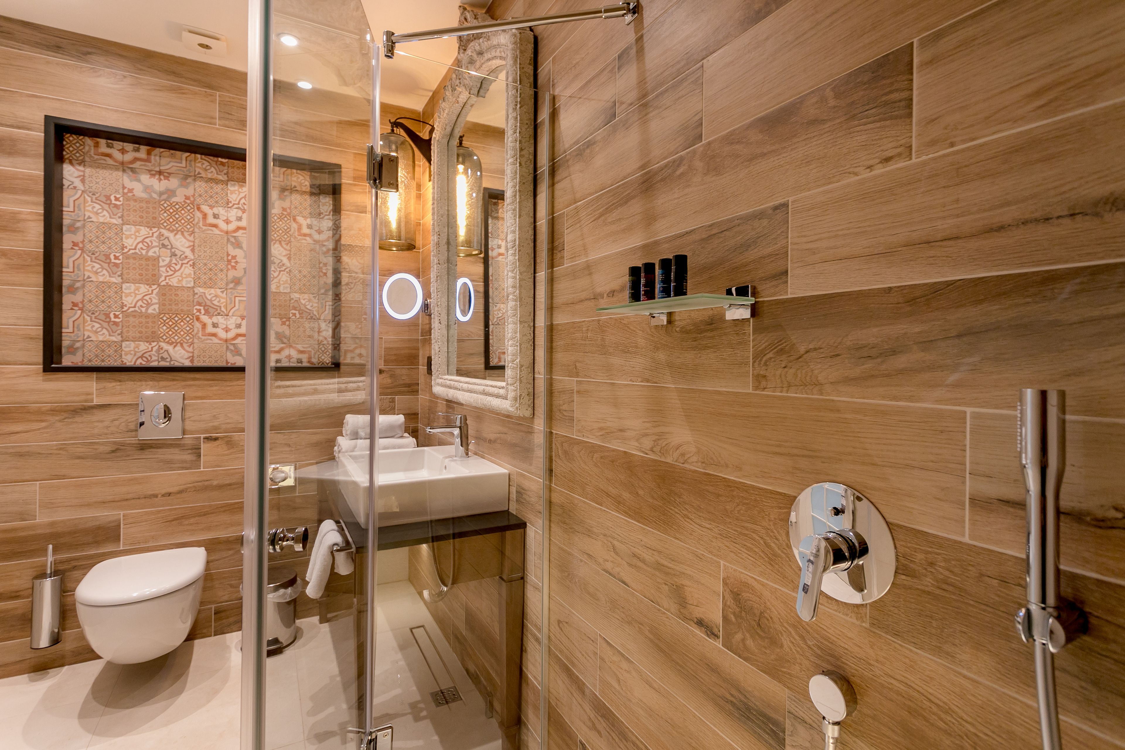 A modern bathroom with a wooden wall, a glass shower enclosure, a sink, and a toilet.
