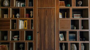 Una estantería de madera con varios compartimentos, cada uno con libros, adornos y pequeñas esculturas.