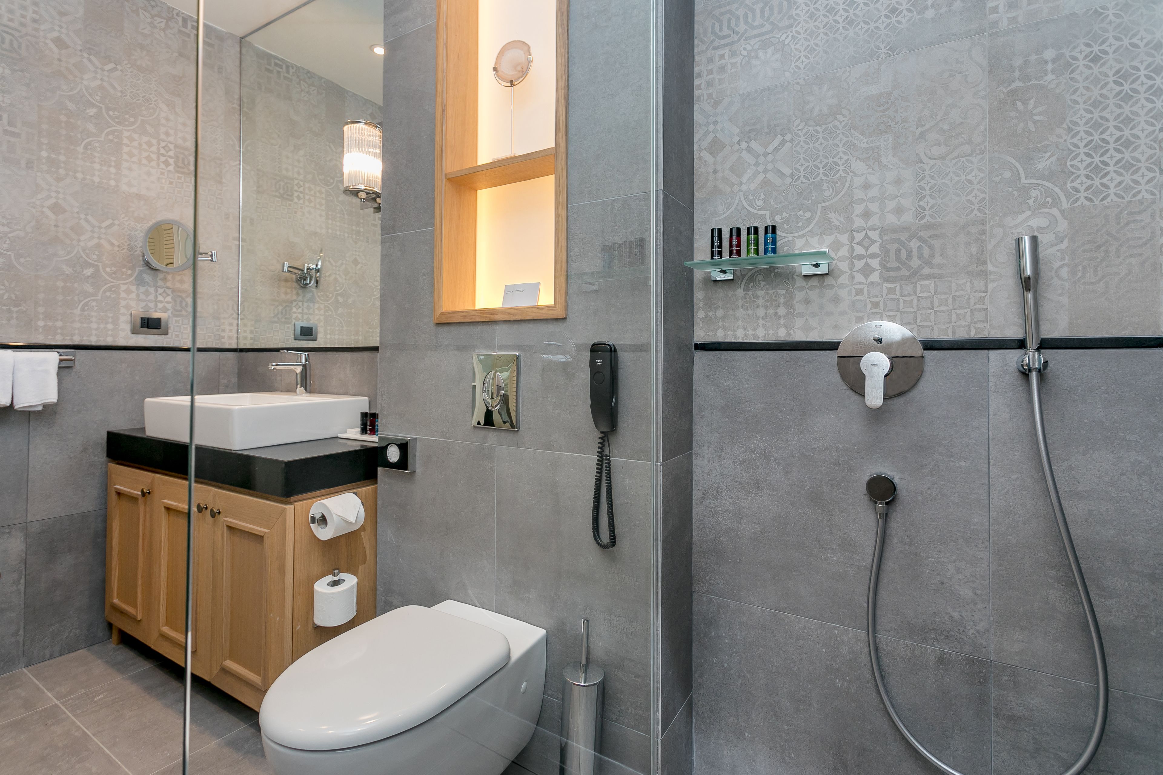 A modern bathroom with a glass shower enclosure, a wooden vanity, and a toilet.