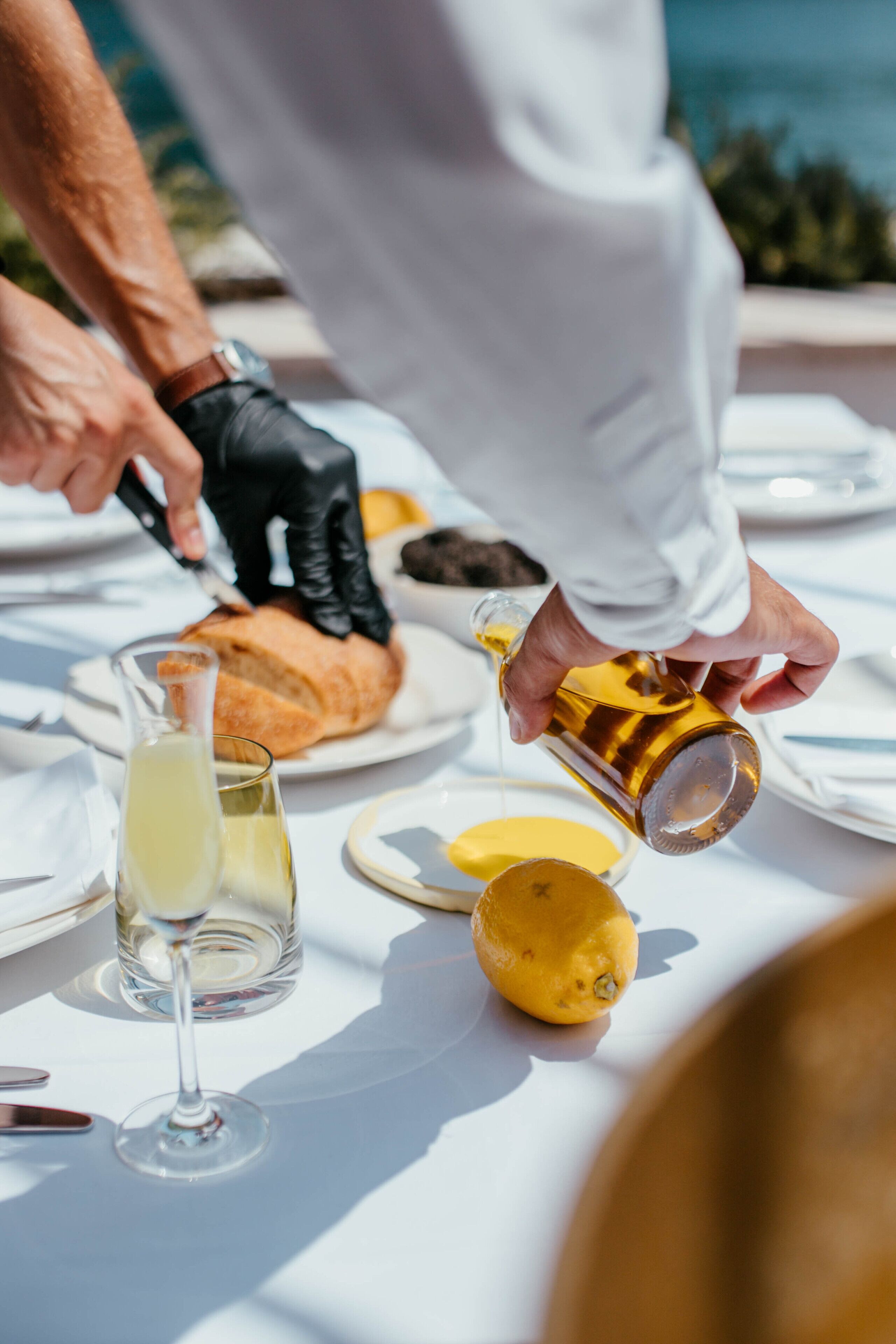 A person pouring a liquid from a bottle onto a plate with a lemon.