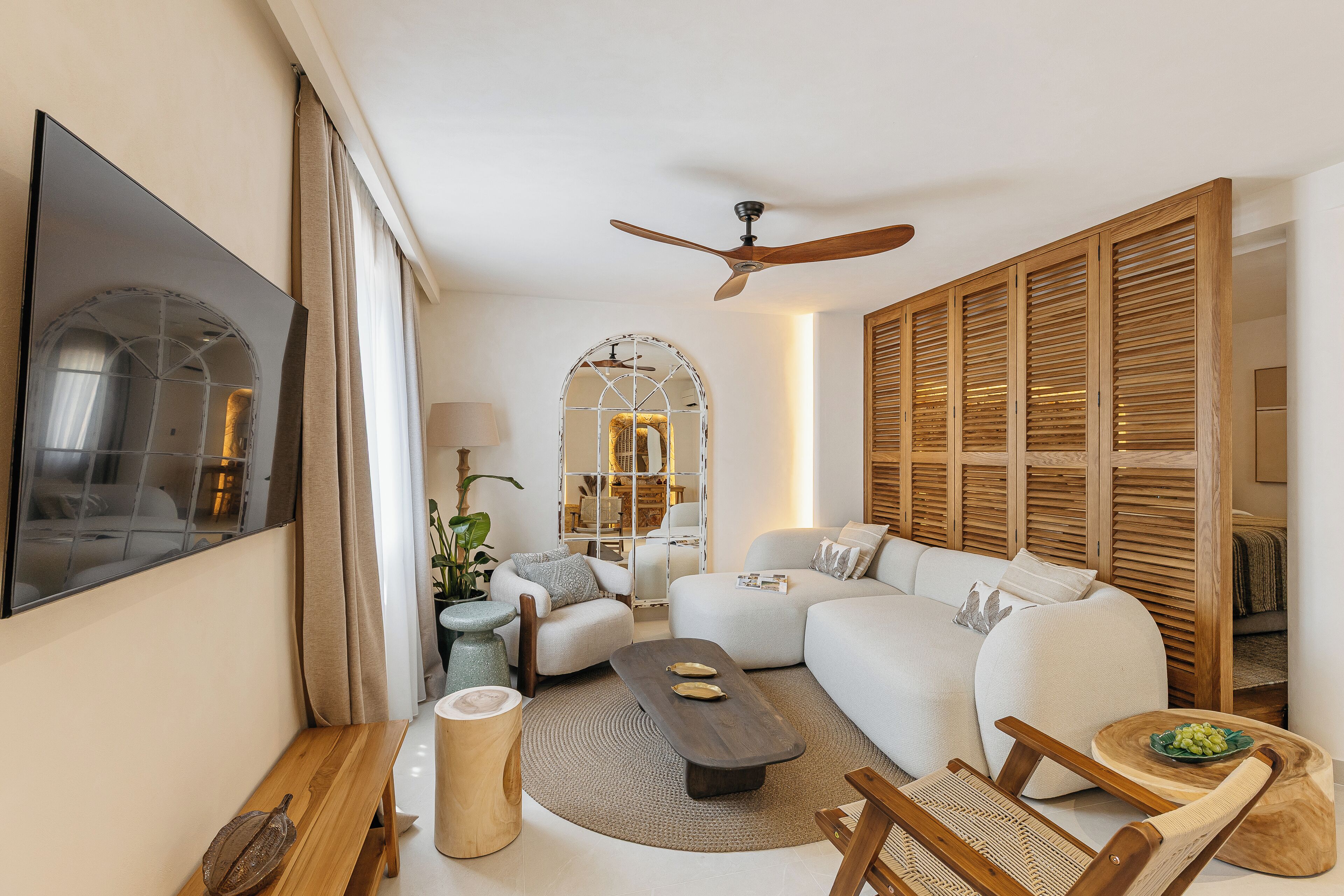 Una sala de estar moderna con un sofá, sillones, una mesa de centro y un ventilador de techo.