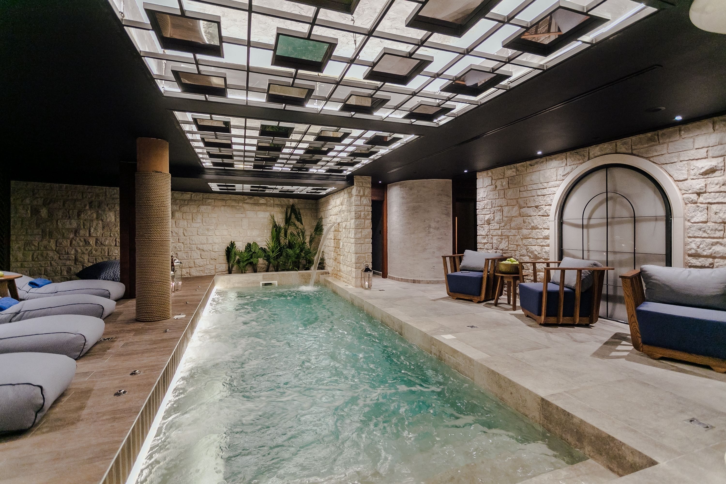 Una piscina interior con pared de piedra y zona de estar.